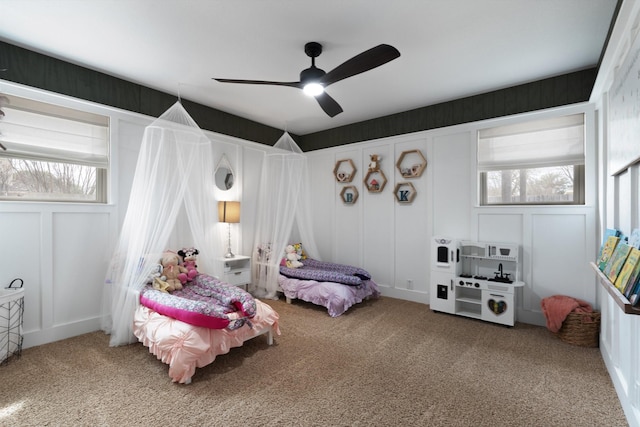 bedroom featuring carpet floors, multiple windows, and a decorative wall