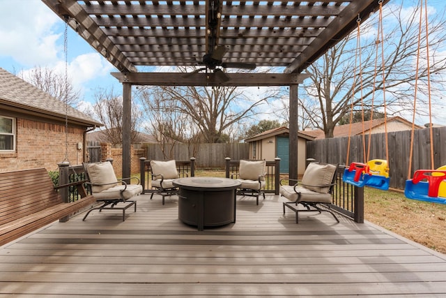 wooden deck featuring an outdoor living space with a fire pit, a fenced backyard, a pergola, and an outbuilding