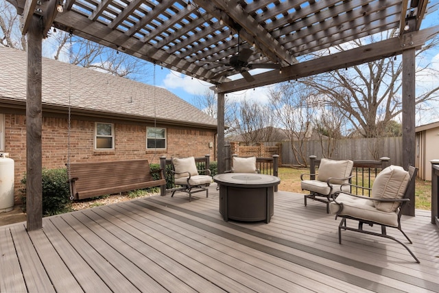 wooden terrace with a ceiling fan, fence, a fire pit, and a pergola