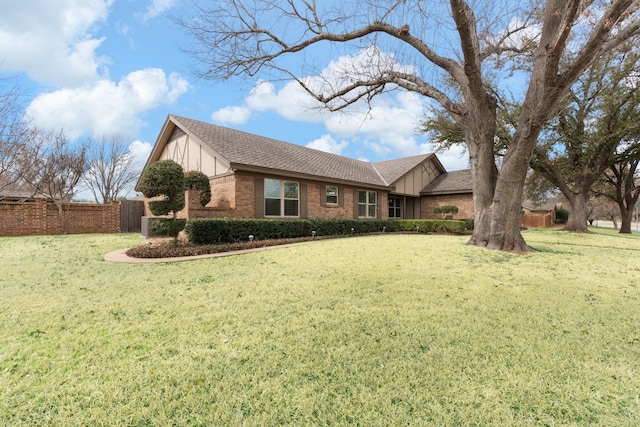 ranch-style house with a shingled roof, a front yard, brick siding, and fence