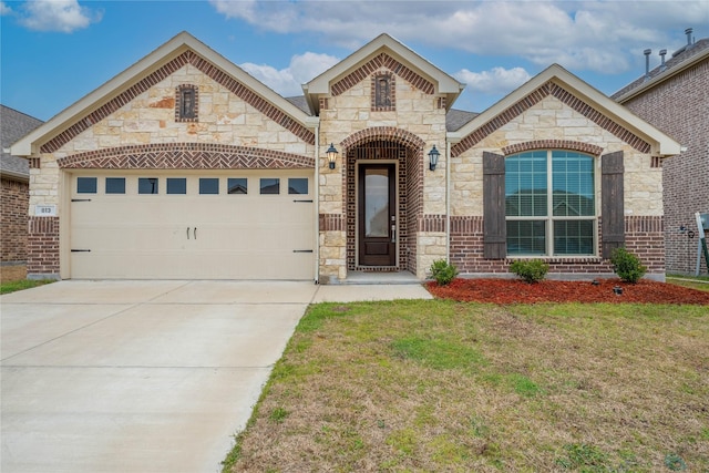 french country inspired facade featuring driveway, a garage, a front lawn, and brick siding