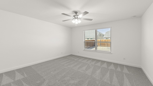 empty room with ceiling fan, light carpet, and baseboards