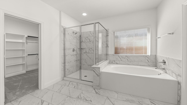 full bathroom with a bath, a marble finish shower, marble finish floor, and a walk in closet