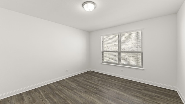 empty room featuring baseboards and dark wood-style floors