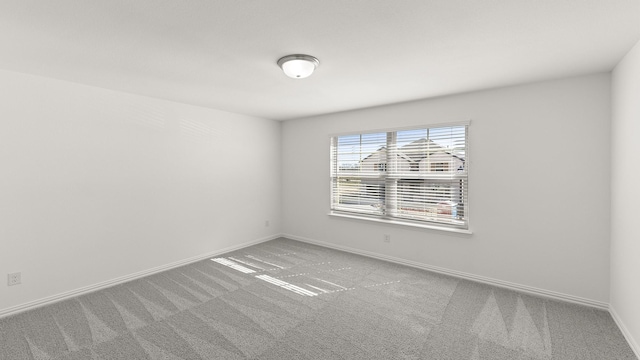 spare room featuring carpet floors and baseboards
