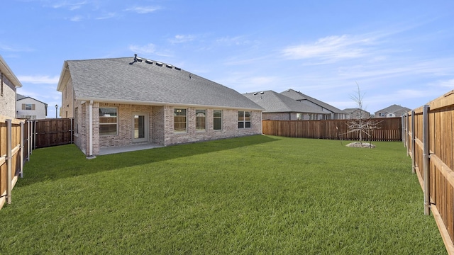 rear view of house with a fenced backyard, brick siding, and a yard
