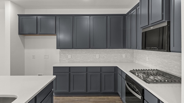 kitchen with stainless steel gas cooktop, decorative backsplash, light countertops, dark wood finished floors, and wall oven