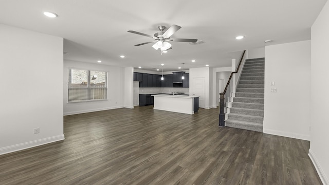 unfurnished living room featuring dark wood-style floors, visible vents, baseboards, stairs, and ceiling fan