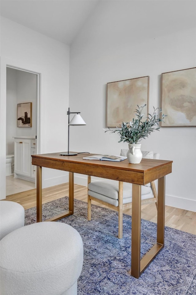 office featuring light wood-type flooring, baseboards, and vaulted ceiling