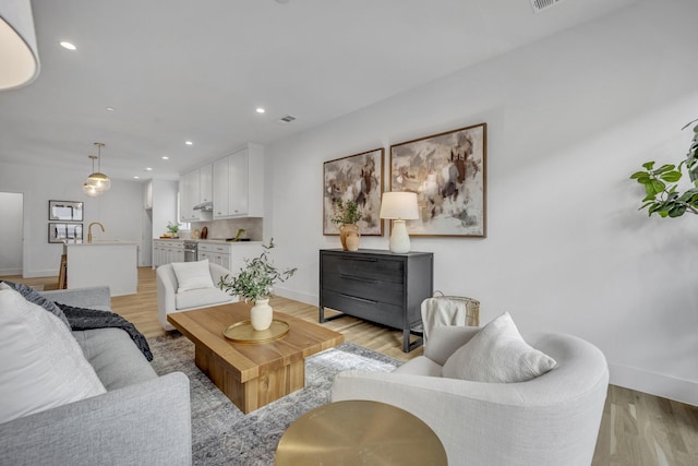 living area with recessed lighting, baseboards, visible vents, and light wood finished floors