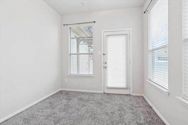 doorway to outside featuring a healthy amount of sunlight, baseboards, and carpet flooring