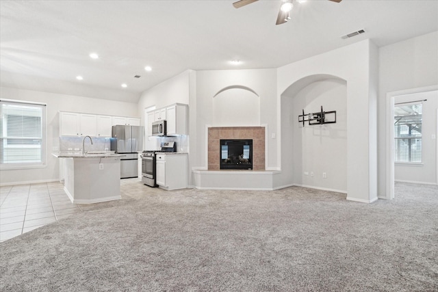 unfurnished living room featuring light tile patterned flooring, recessed lighting, light carpet, visible vents, and a tiled fireplace