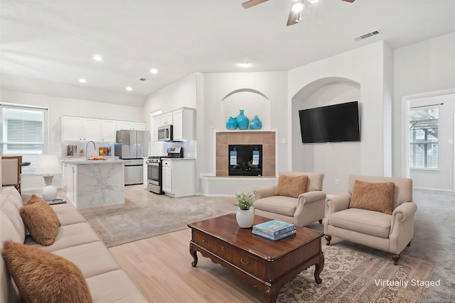 1931 Antebellum Ct, Savannah, TX 76227 - living room featuring light wood-type flooring, visible vents, recessed lighting, a ceiling fan, and a tile fireplace