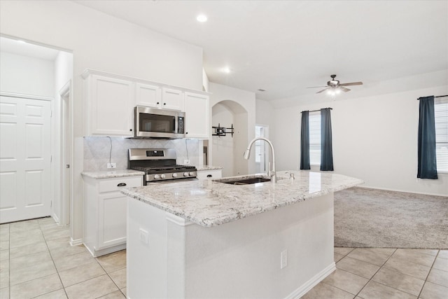 kitchen featuring light tile patterned floors, white cabinets, a sink, stainless steel appliances, and backsplash