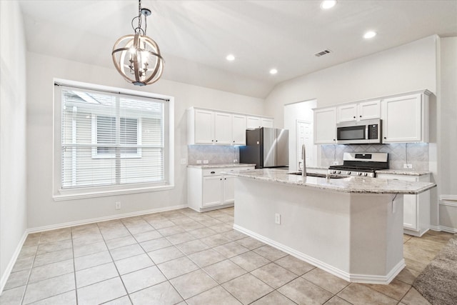 kitchen with visible vents, white cabinets, appliances with stainless steel finishes, light stone countertops, and a center island with sink