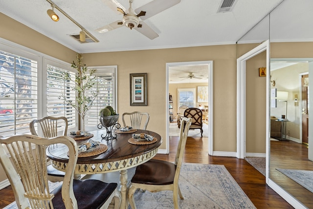 dining space with dark wood-style floors, a wealth of natural light, visible vents, and crown molding