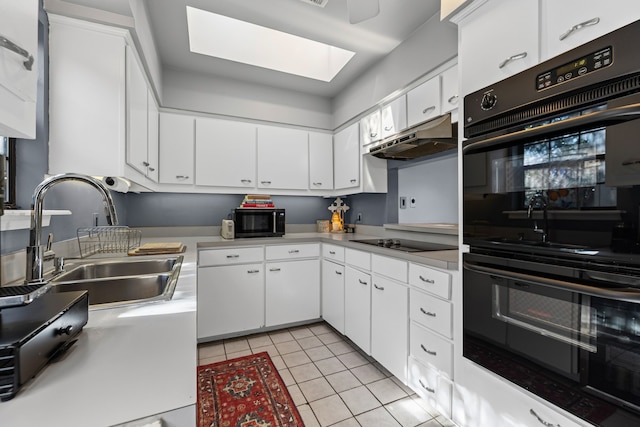 kitchen with light tile patterned floors, under cabinet range hood, a sink, light countertops, and black appliances