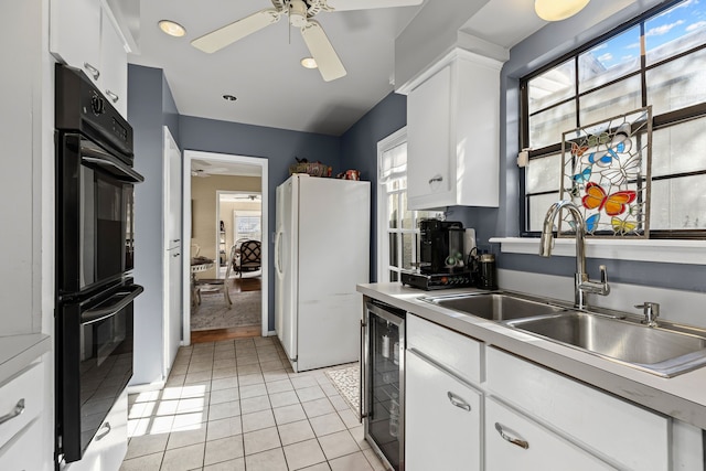 kitchen with light tile patterned floors, wine cooler, dobule oven black, a sink, and freestanding refrigerator