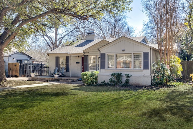 ranch-style home with a chimney, a shingled roof, a porch, fence, and a front lawn