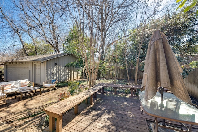 wooden terrace with an outdoor hangout area, a detached garage, and a fenced backyard