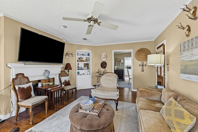 living room featuring a textured ceiling, ceiling fan, wood finished floors, visible vents, and baseboards