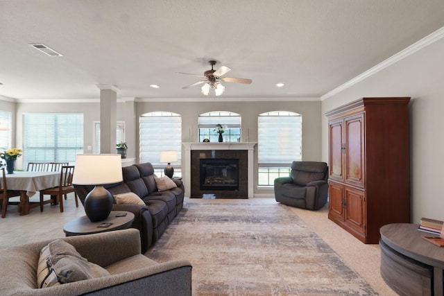 living room featuring visible vents, a ceiling fan, light colored carpet, a glass covered fireplace, and ornamental molding