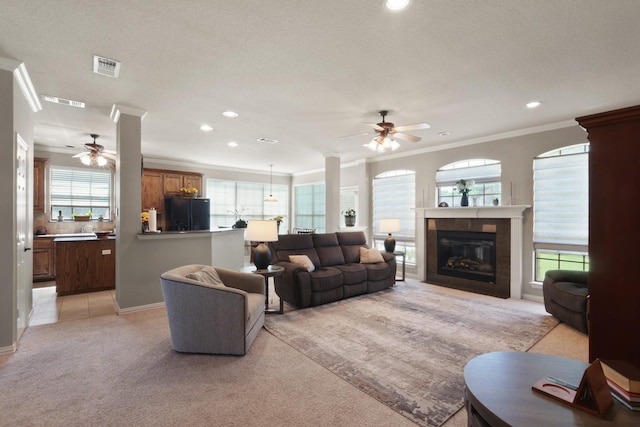 living room with visible vents, ornamental molding, a ceiling fan, and light colored carpet