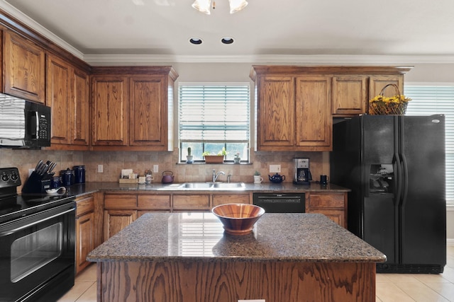 kitchen featuring brown cabinetry, a sink, black appliances, and a kitchen island