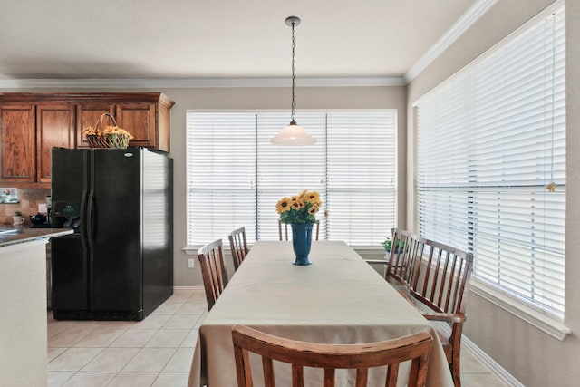 dining area with a healthy amount of sunlight, light tile patterned flooring, crown molding, and baseboards