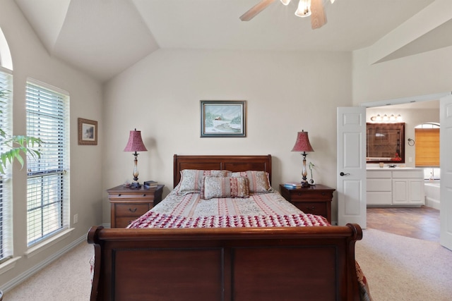 bedroom with a ceiling fan, lofted ceiling, light colored carpet, and ensuite bathroom