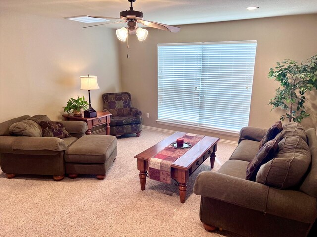 living area with baseboards, a ceiling fan, and light colored carpet