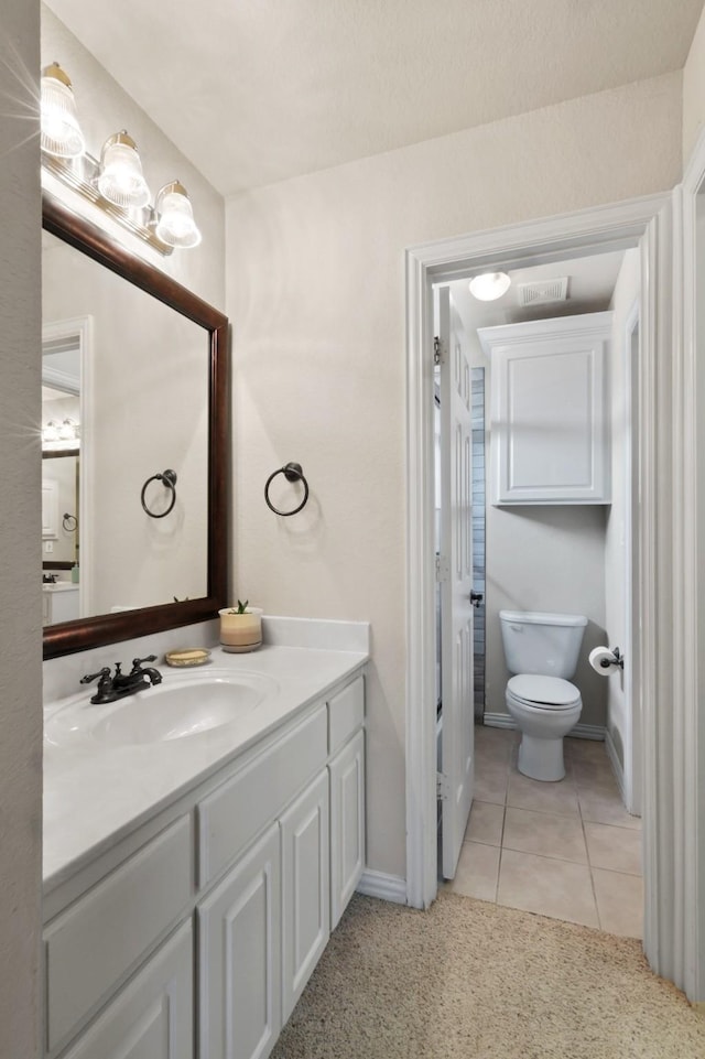 bathroom featuring tile patterned flooring, baseboards, vanity, and toilet