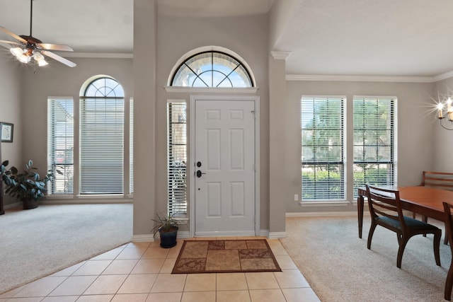 foyer featuring light carpet, light tile patterned floors, plenty of natural light, and ornamental molding