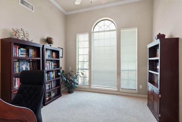 carpeted office with ornamental molding, a wealth of natural light, visible vents, and a ceiling fan