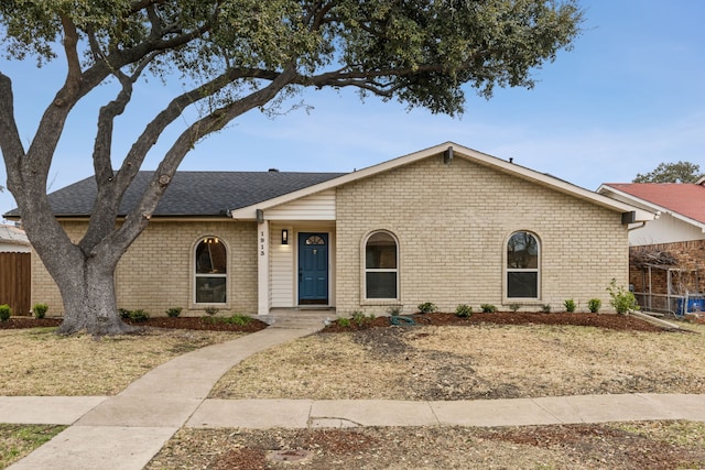 view of front of property featuring a shingled roof, fence, and brick siding