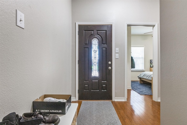 entryway with a textured wall, wood finished floors, and baseboards