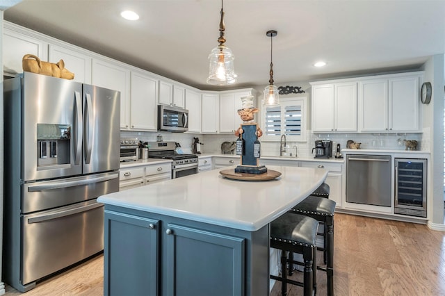 kitchen with stainless steel appliances, a breakfast bar, beverage cooler, and white cabinets