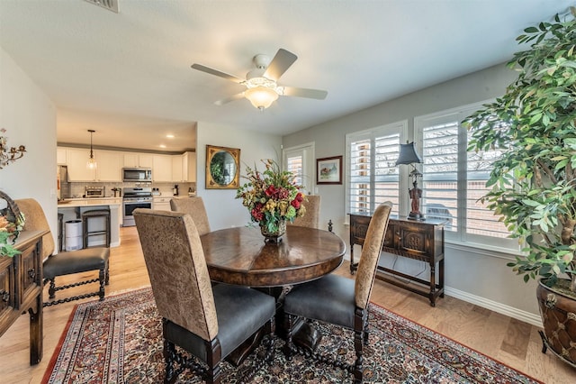 dining room with light wood-style floors, baseboards, and ceiling fan