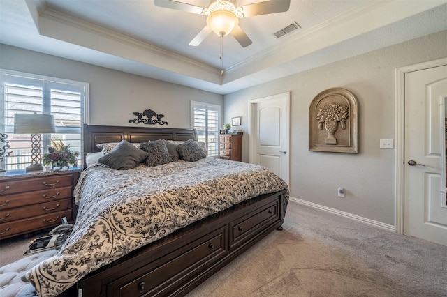 bedroom with a tray ceiling, ornamental molding, visible vents, and light carpet