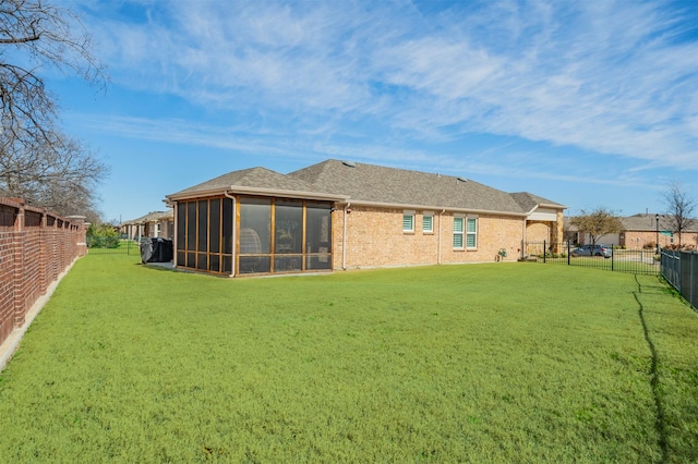 rear view of house with a fenced backyard, brick siding, a yard, and a sunroom