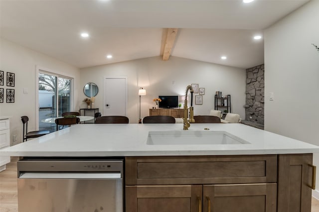 kitchen featuring vaulted ceiling with beams, light wood-style flooring, a sink, open floor plan, and stainless steel dishwasher