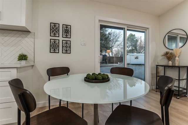 dining area featuring light wood-style flooring and baseboards