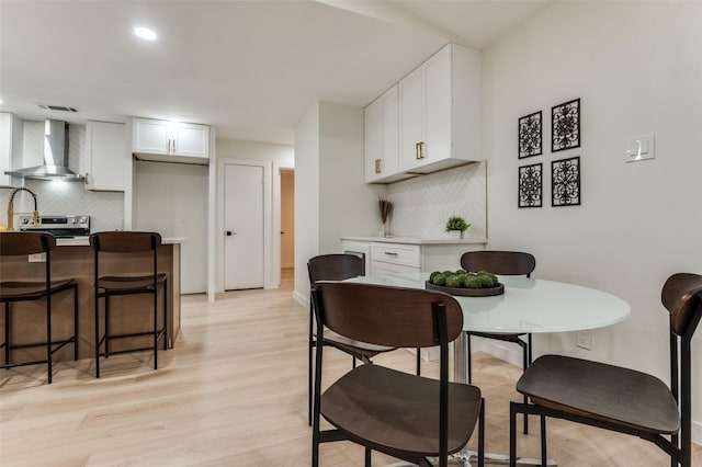 dining area featuring visible vents, light wood-style flooring, and baseboards