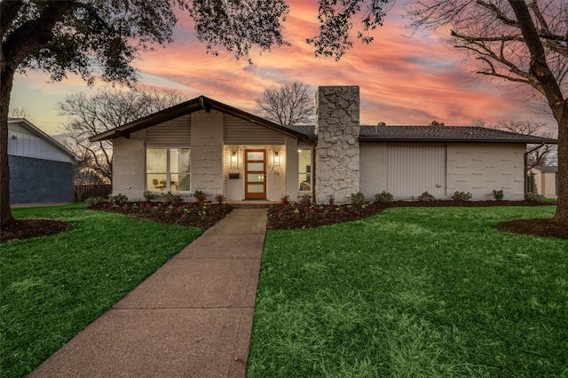 mid-century modern home featuring a yard, brick siding, and a chimney