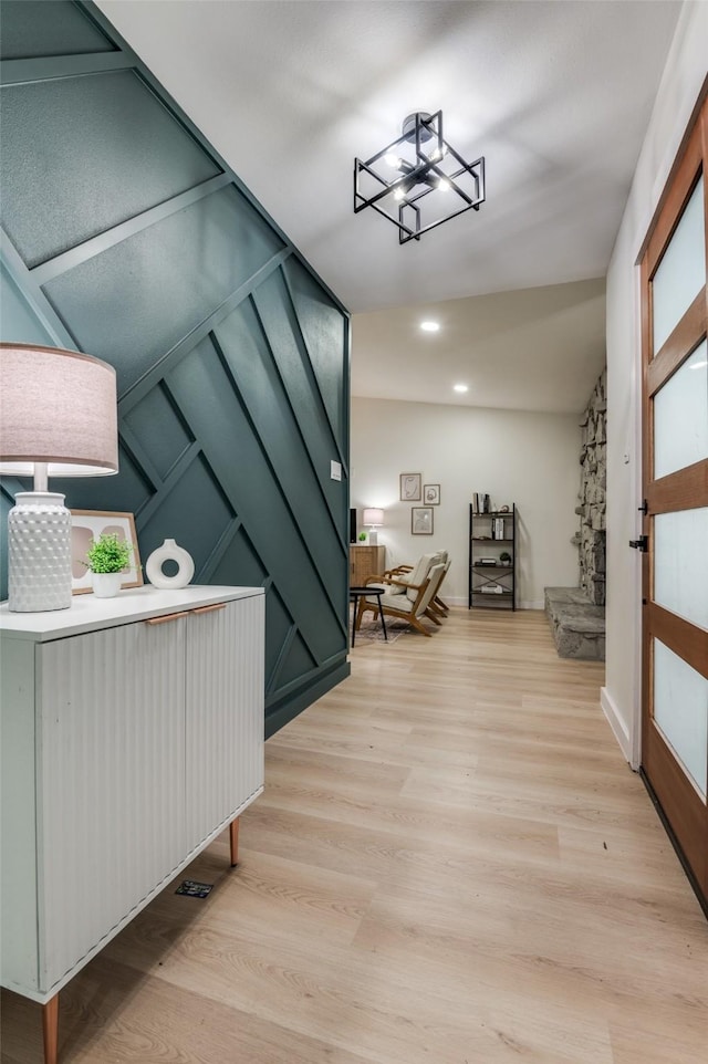 corridor with a chandelier, light wood-type flooring, and recessed lighting