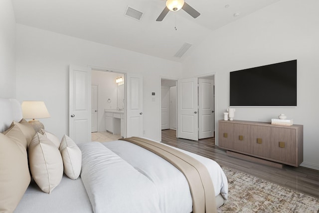 bedroom featuring visible vents, ensuite bathroom, wood finished floors, ceiling fan, and vaulted ceiling