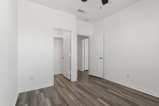 unfurnished bedroom featuring a walk in closet, visible vents, dark wood-style flooring, and baseboards