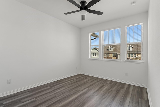 unfurnished room featuring baseboards, dark wood-type flooring, and a ceiling fan