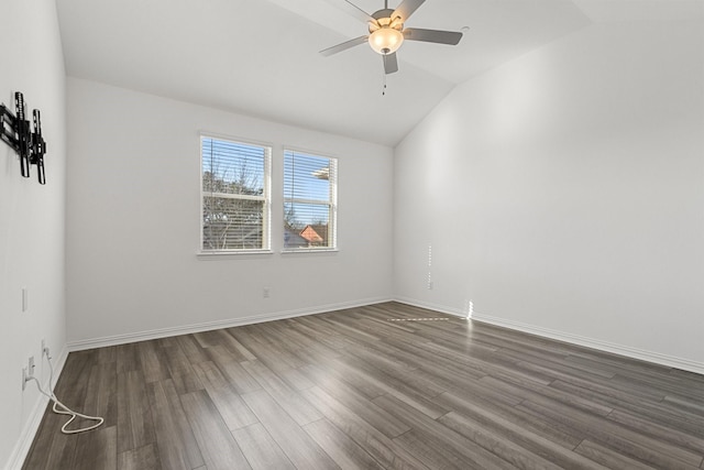 empty room with a ceiling fan, vaulted ceiling, dark wood-style floors, and baseboards