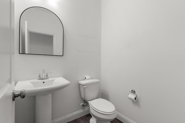 bathroom with a sink, baseboards, toilet, and wood finished floors